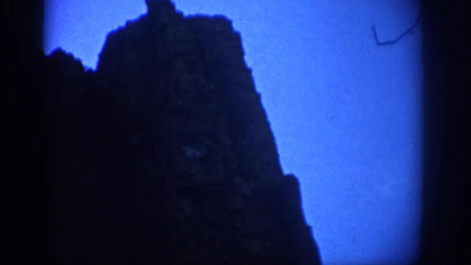 Colorado 8mm frame showing a dark rocky formation against a vivid blue sky after the tunnel passage.