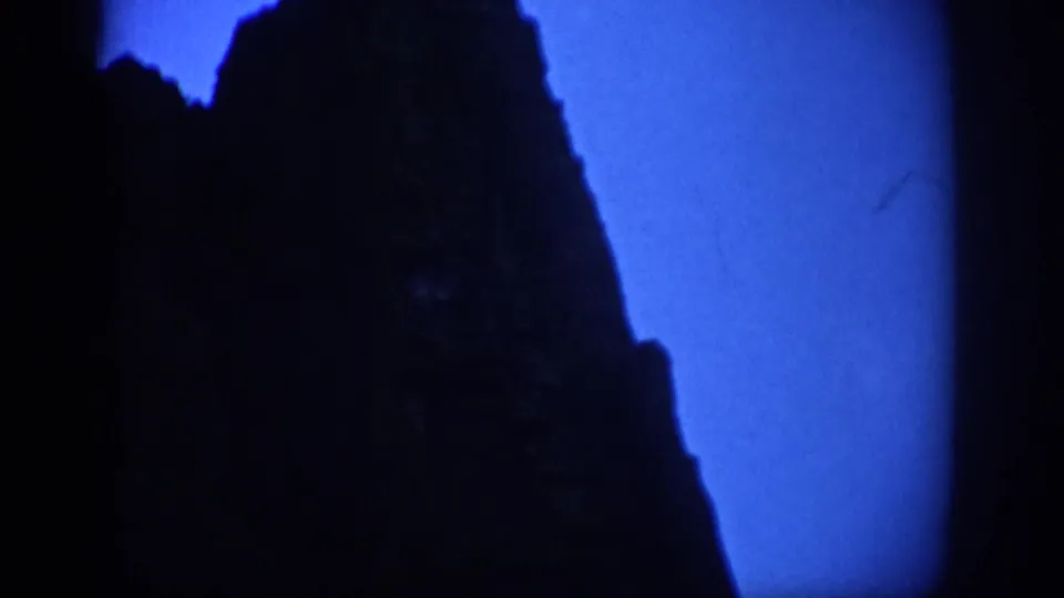 1959 Colorado 8mm frame showing a dark mountainside silhouette against a saturated blue twilight sky.