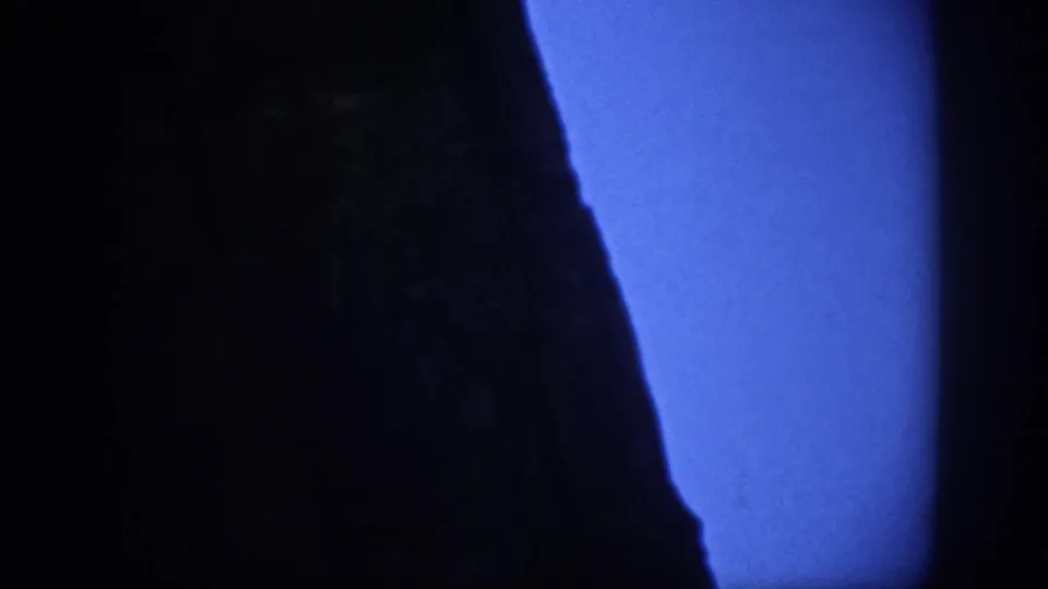 1959 8mm view of a dark Colorado mountainside, held close against a cool blue sky.