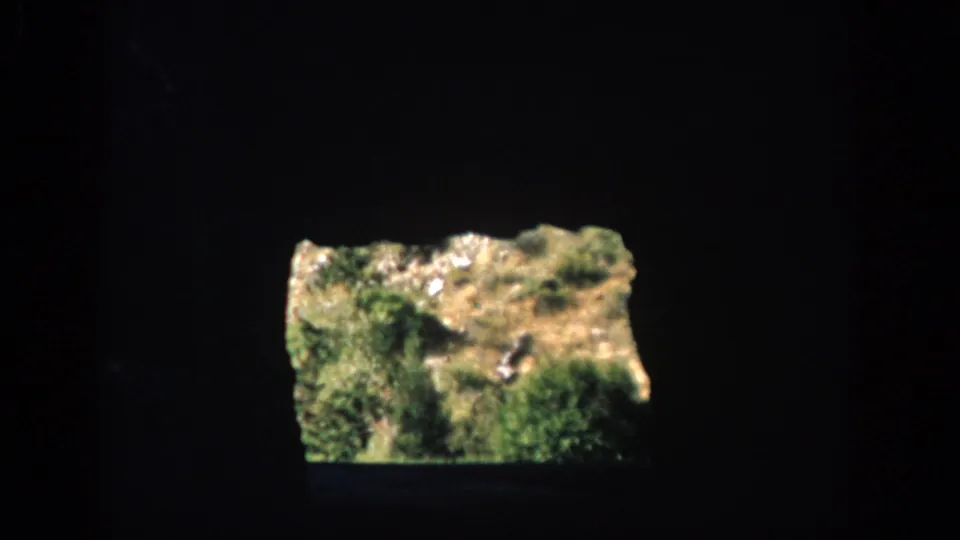 The final 1959 Colorado 8mm frame holds on a bright grassy rock formation within a dark cave-like view.