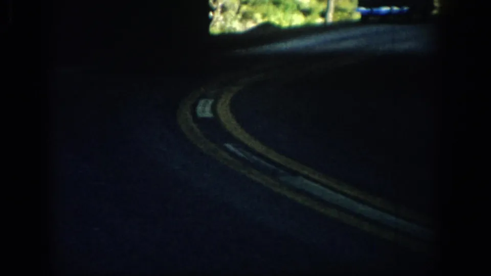 Curving rural Colorado road with double yellow centerlines, filmed from inside a moving car in 1959.