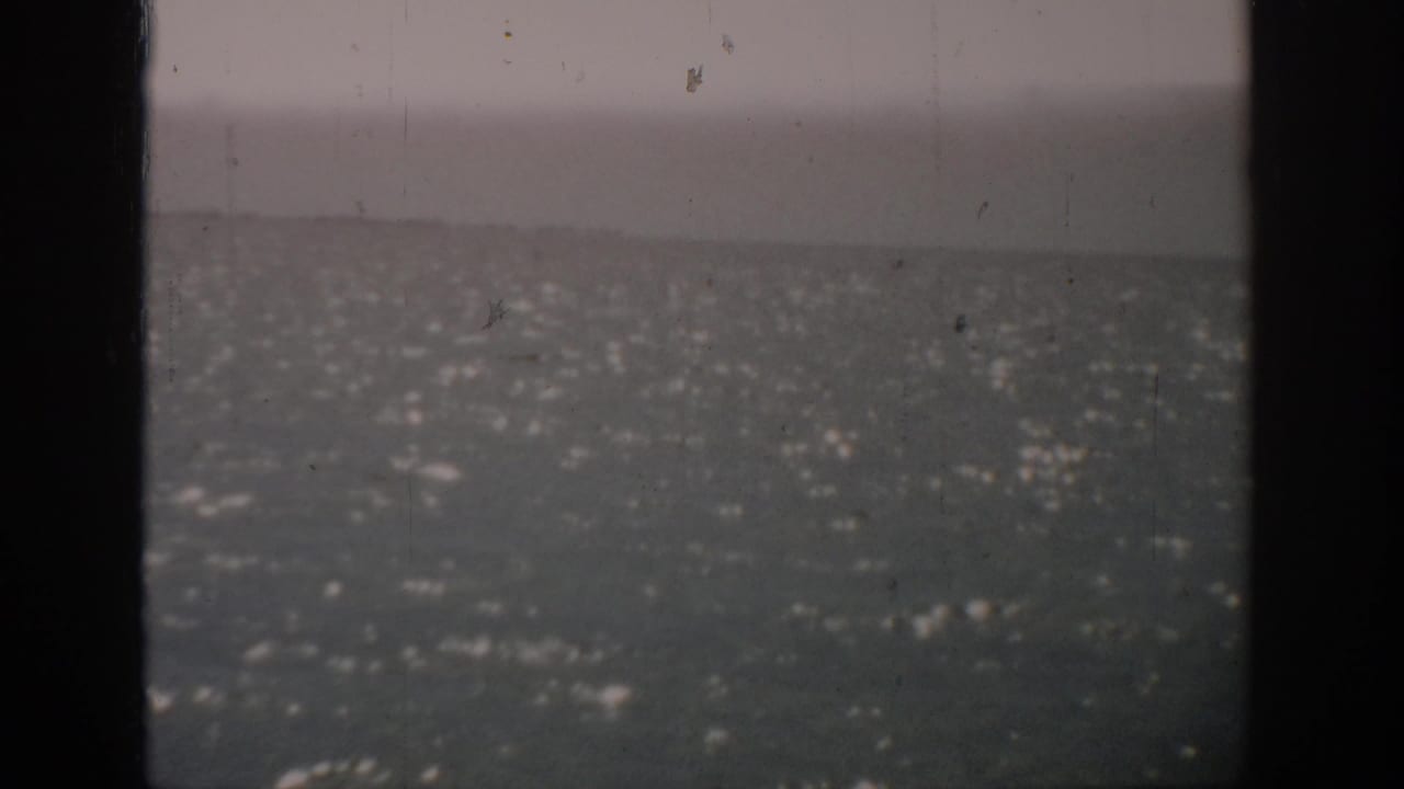 1959 Florida home-movie frame showing open water under an overcast sky, with dark vertical borders and visible film wear.