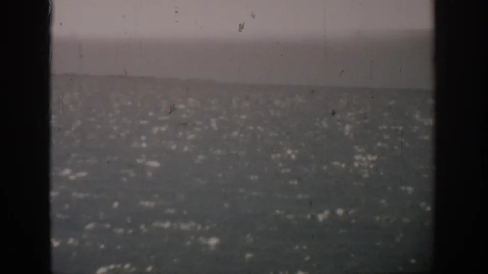 1959 Florida home-movie frame showing open water under an overcast sky, with dark vertical borders and visible film wear.