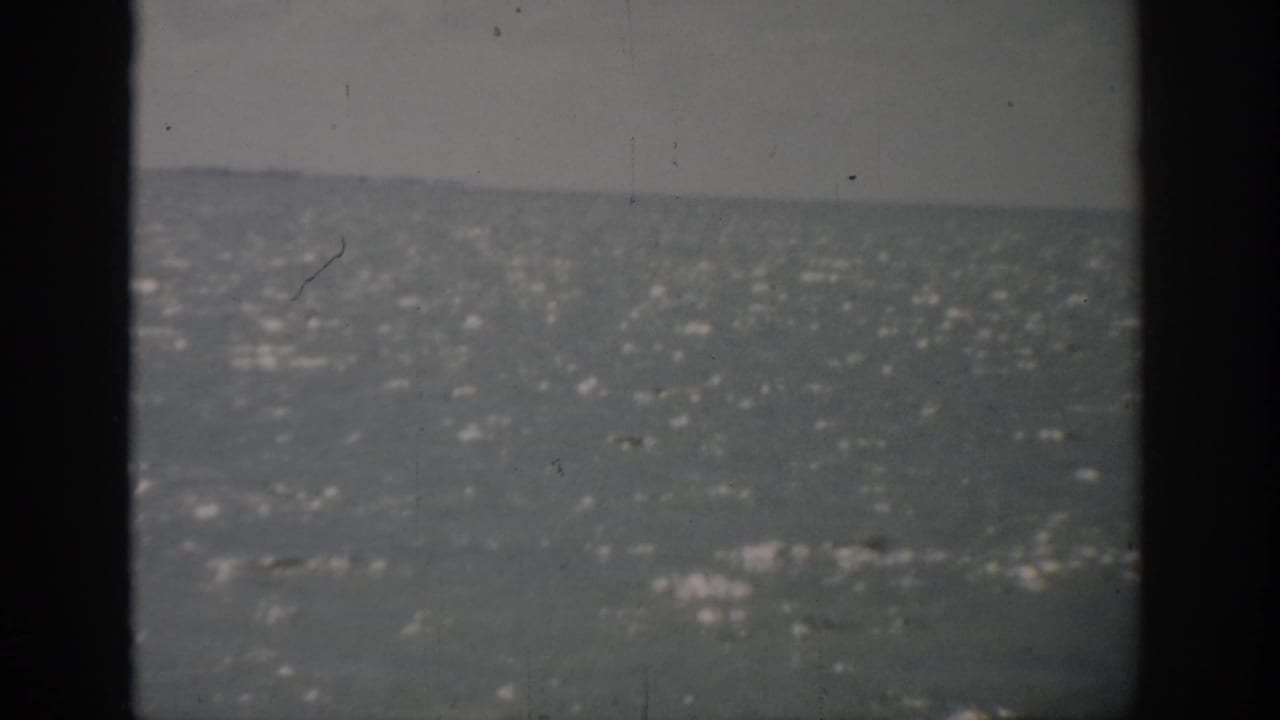 Wide water surface with a muted horizon, seen between dark vertical frame bands.