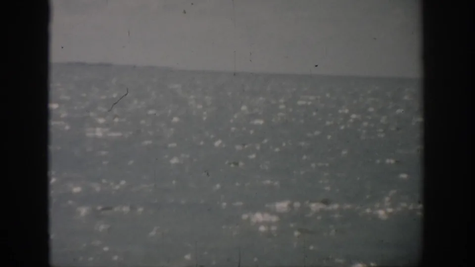 1959 Florida 8mm frame of shimmering water and distant horizon, partially obscured by dark vertical bands from the film or camera view.