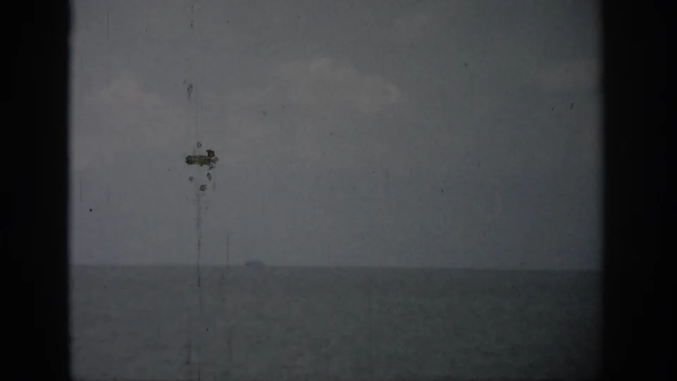 1959 Florida 8mm frame of a subdued ocean horizon, cloudy sky, and visible film wear.