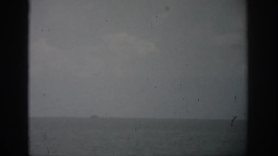 1959 Florida home-movie frame showing open water and pale cloud cover through an aged 8mm frame.