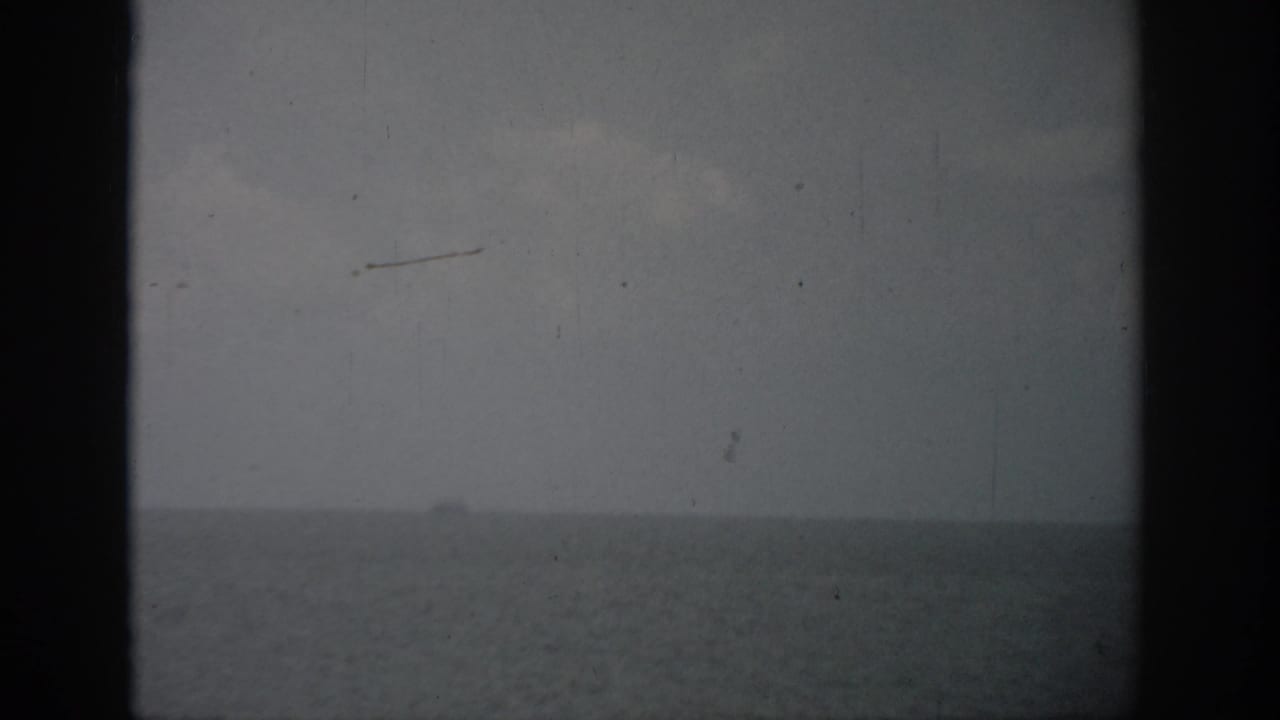 Hazy sea horizon under gray sky with a small distant boat.