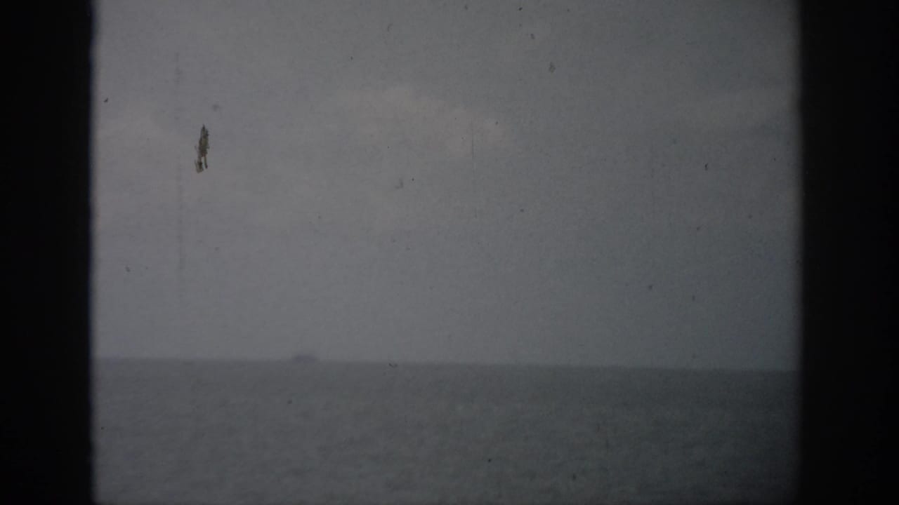 Distant boat on a hazy sea horizon seen through 8mm film grain.