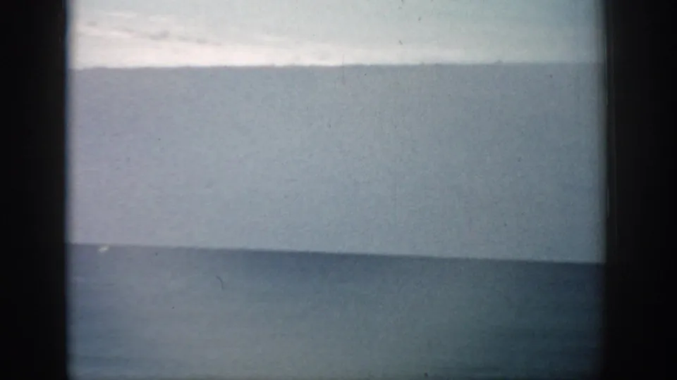 Florida 8mm frame showing a brief view across ocean or large water toward a hazy horizon.