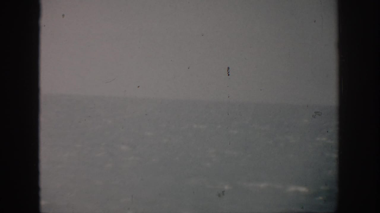 Open ocean and horizon with faint wave highlights and dark vertical film borders.