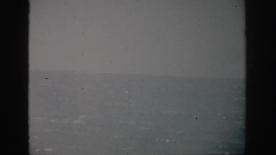 Soft 8mm view of the Florida ocean and pale sky, with visible grain, dust, and dark gate edges.