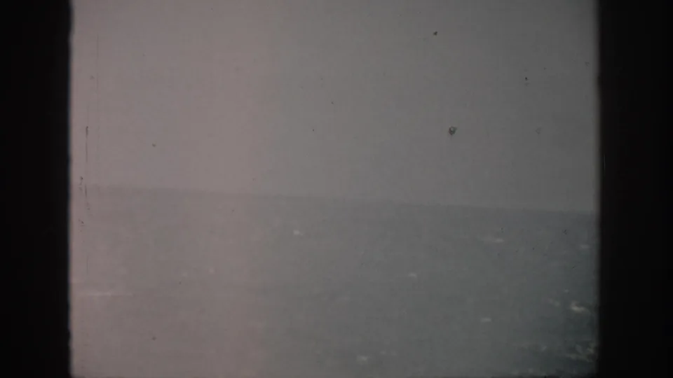 1959 Florida 8mm frame showing a soft gray sea horizon beneath gloomy sky, bordered by dark film edges and visible dust.