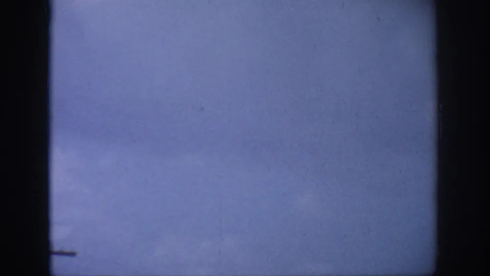1959 Florida 8mm frame after the camera tilts up to a pale blue sky with faint cloud tone.
