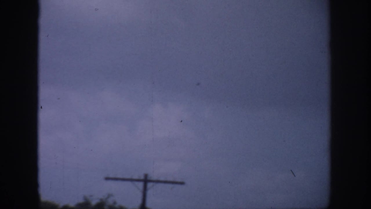 Cloudy sky behind a central dark frame with a telephone pole near the lower edge.
