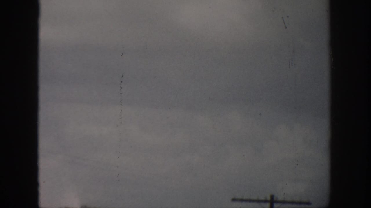 1959 Florida 8mm frame showing a muted ocean horizon, faint distant ship, and dark home-movie frame edges.