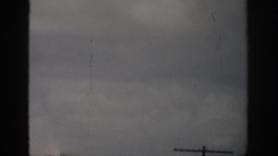 1959 Florida 8mm frame showing a muted ocean horizon, faint distant ship, and dark home-movie frame edges.