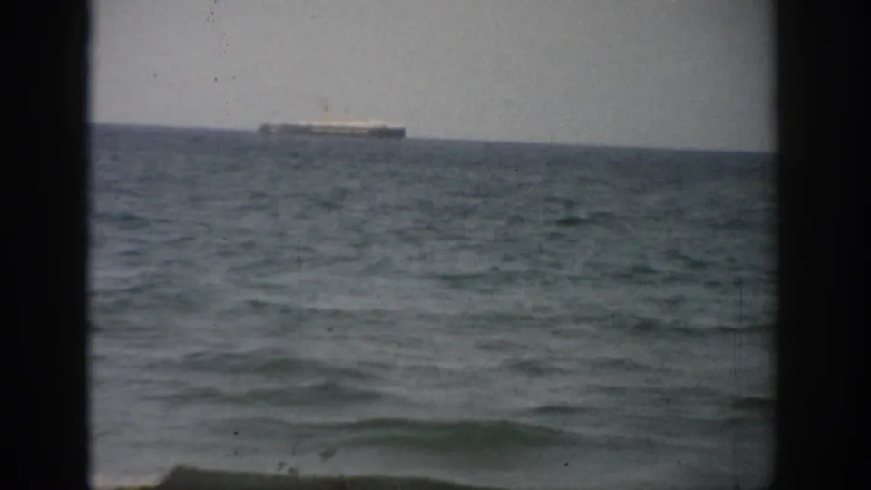 1959 Florida home-movie frame with a distant vessel near the horizon and rippled sea filling the foreground.