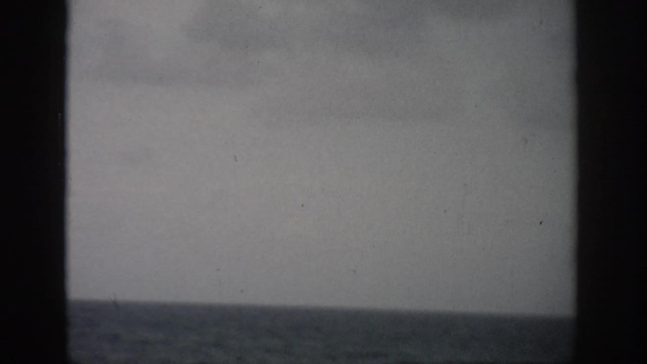 Open ocean and cloudy sky divided by dark vertical framing.
