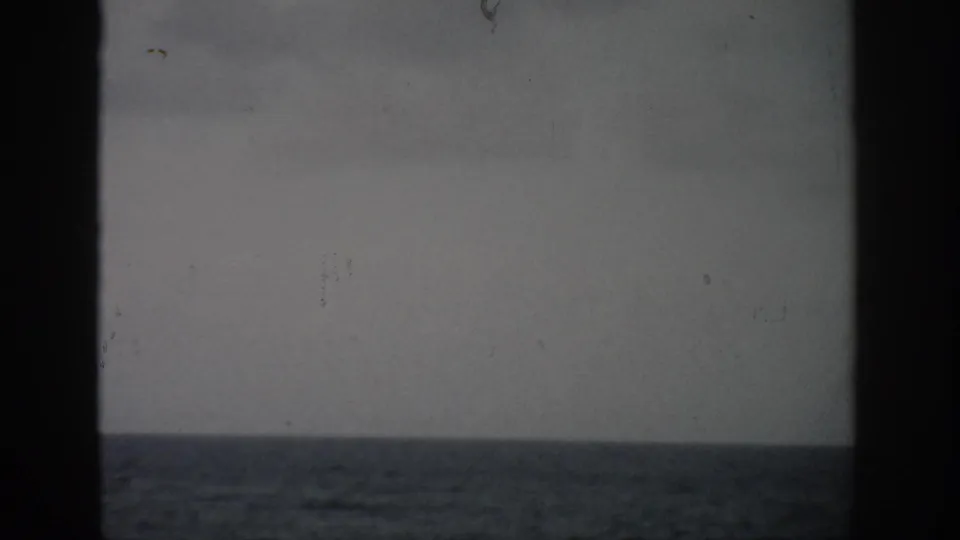 Faded 1959 Florida 8mm view of pale sky and ocean bands, with dark frame edges and visible film dust.