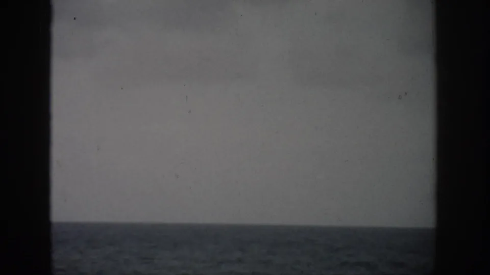 1959 Florida coastal frame showing calm open water and a pale cloudy sky, with dark framing at the sides and center.