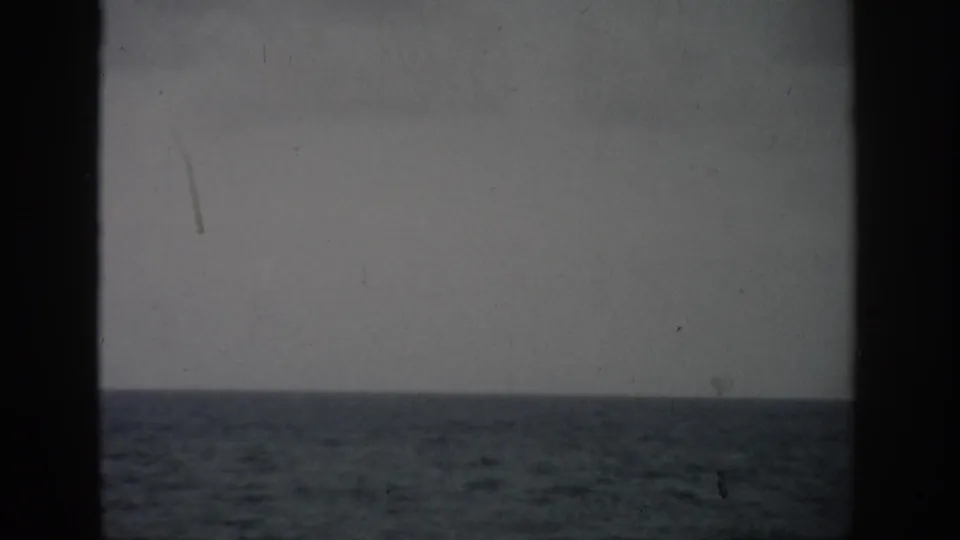 1959 Florida 8mm home-movie frame showing a muted ocean horizon and small surf through dark window-like borders.