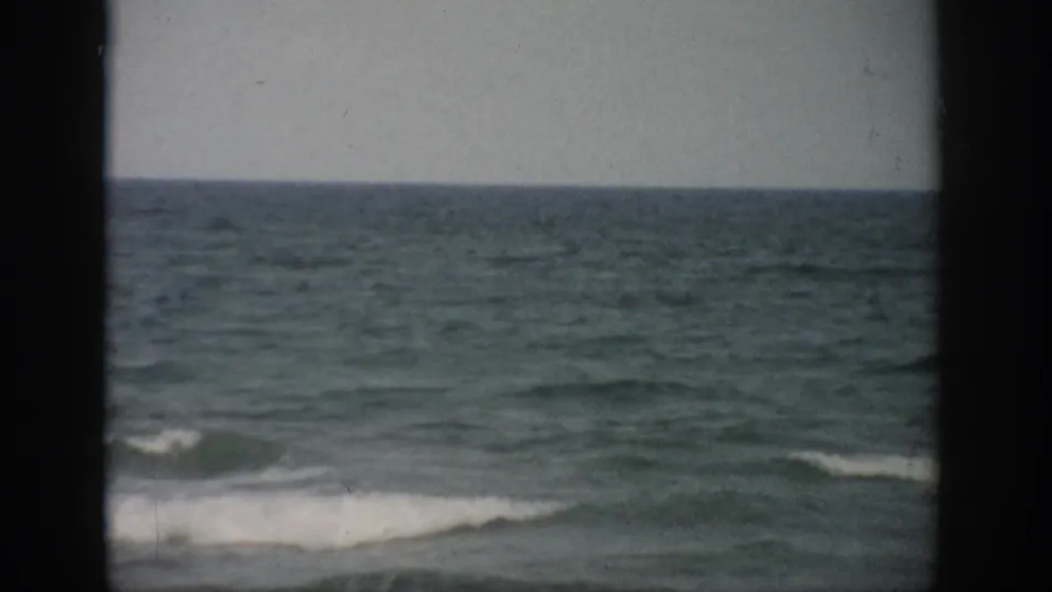 1959 Florida home-movie view of low surf near shore, with ocean water and horizon held between dark frame borders.