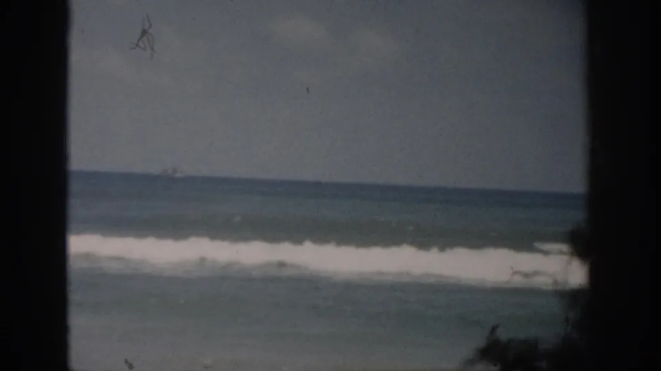 1959 Florida 8mm view of rolling ocean surf beneath a gray-blue sky, framed by dark window edges.