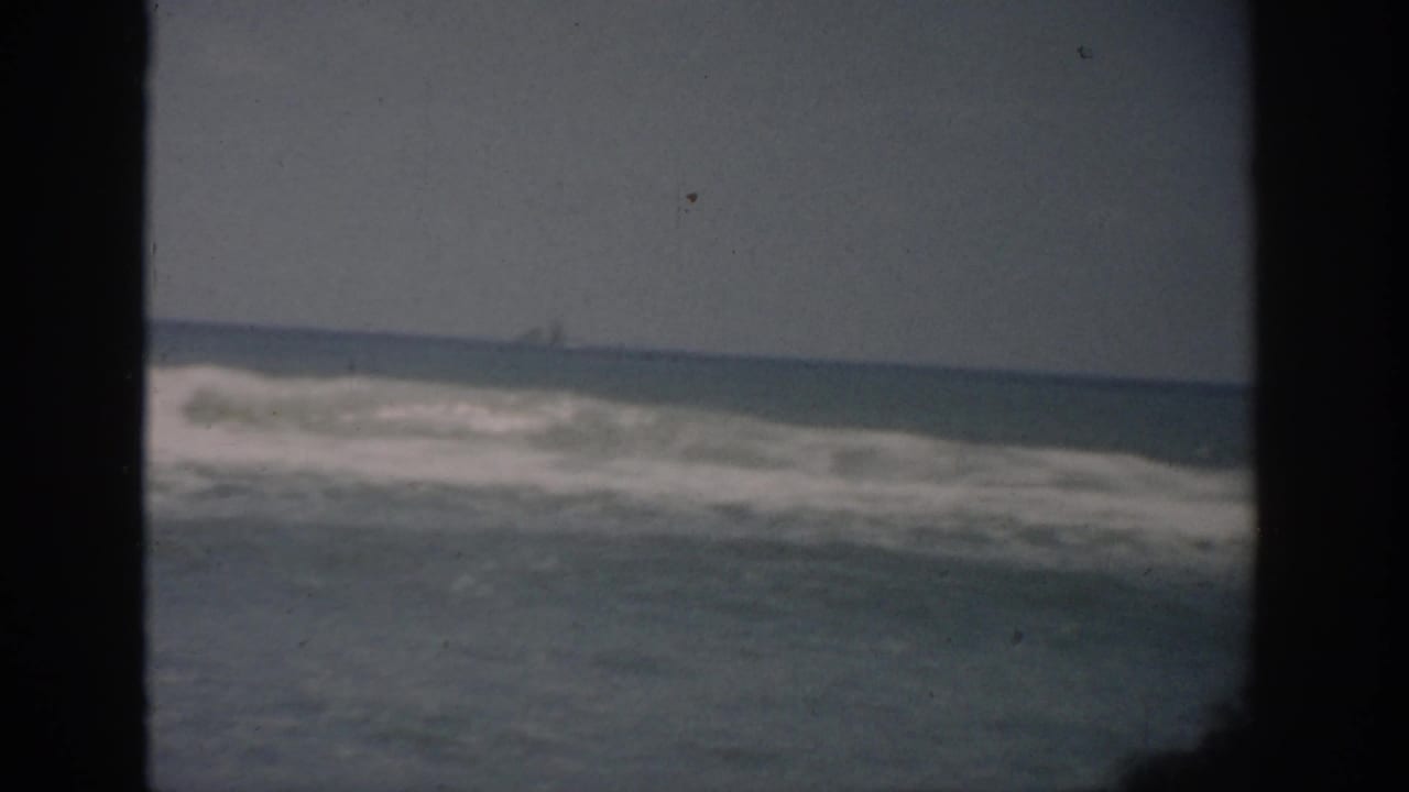 Breaking waves on the ocean with a dark window frame at the left and center.