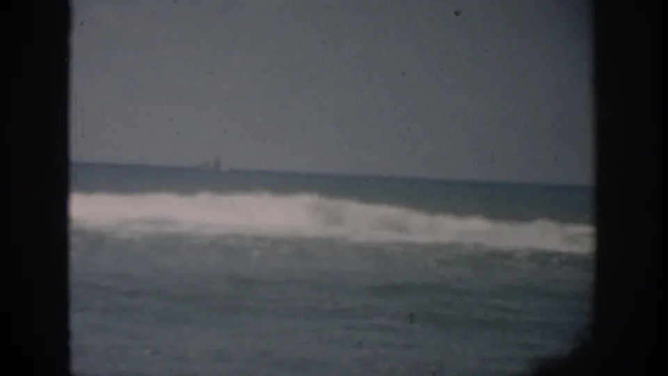 1959 Florida ocean scene showing low rolling surf, horizon, and a faint distant vessel-like shape through the window.