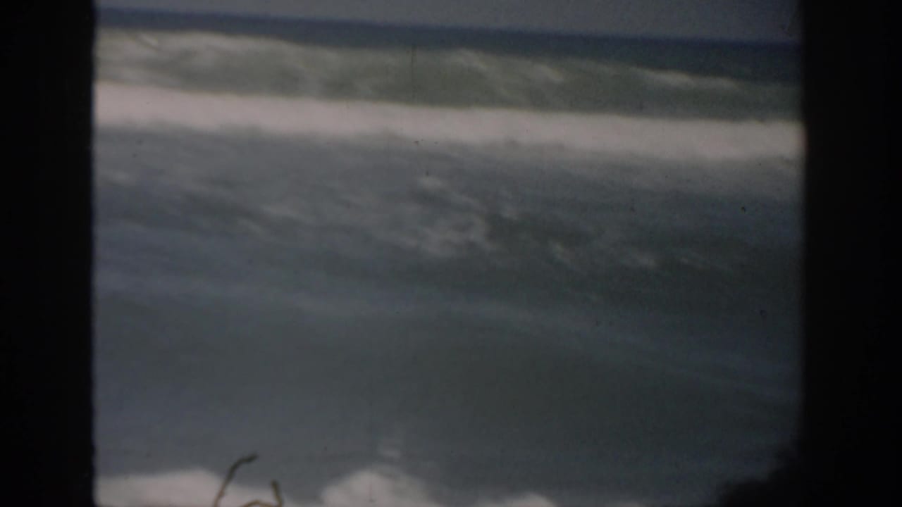 Ocean waves breaking beneath a pale sky within dark 8mm frame borders.