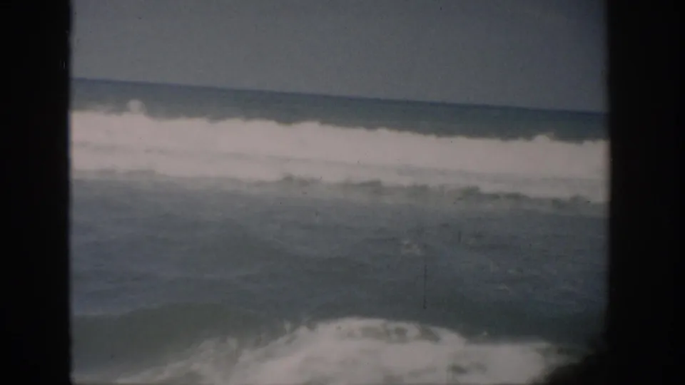 1959 Florida 8mm frame showing a breaking ocean wave and foamy water, with soft focus and visible film-frame edges.