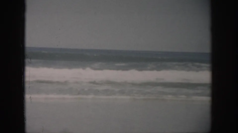 1959 Florida 8mm frame showing surf breaking onto a sandy shoreline under an overcast sky, with dark reel borders visible.