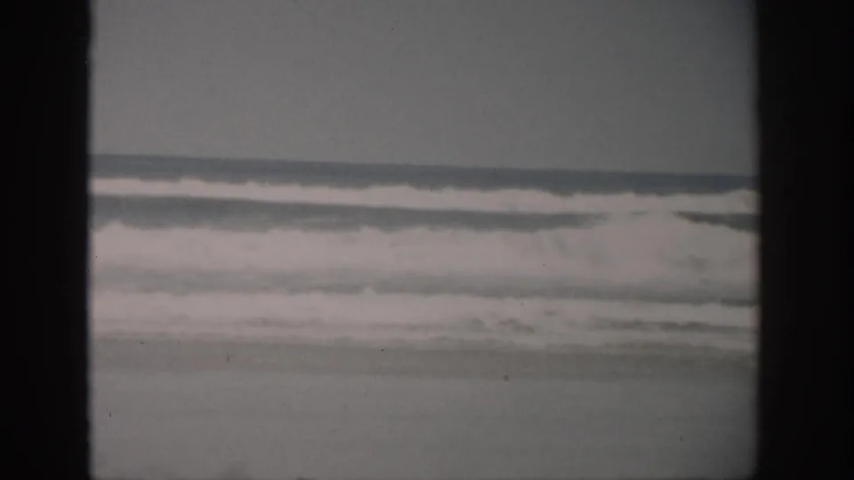 1959 Florida 8mm frame showing low surf bands and an overcast coastal horizon, with soft focus and film grain.