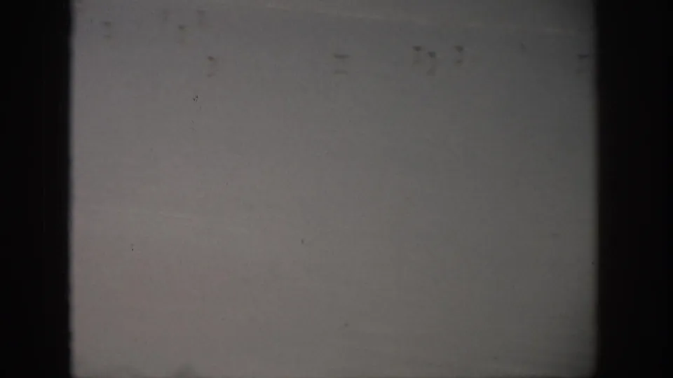 1959 Florida 8mm frame showing a quiet shoreline with low waves, wet sand, muted sky, and visible film gate edges.