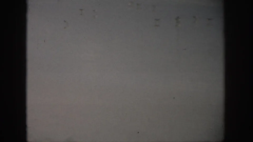 1959 Florida home-movie still of waves breaking offshore, with wet sand in the foreground and dark 8mm frame borders.