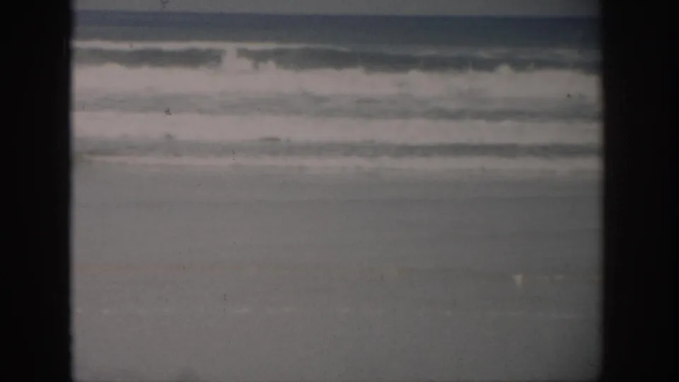 1959 Florida 8mm beach view with a wide breaker, soft focus, wet sand, and the scan's dark edge framing.