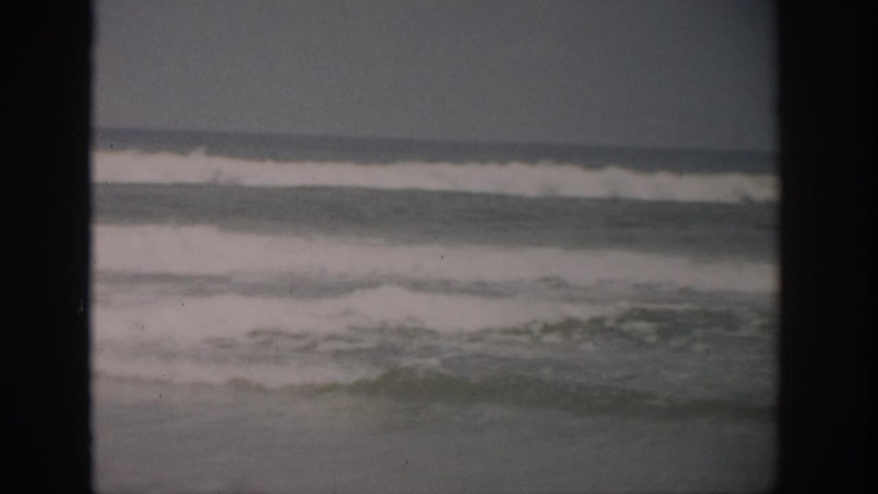 Gray ocean waves breaking under an overcast sky with dark 8mm frame edges.