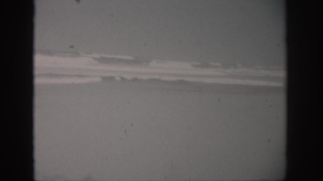 1959 Florida 8mm frame showing rough ocean water and a low, cloudy horizon with visible film grain and dust.