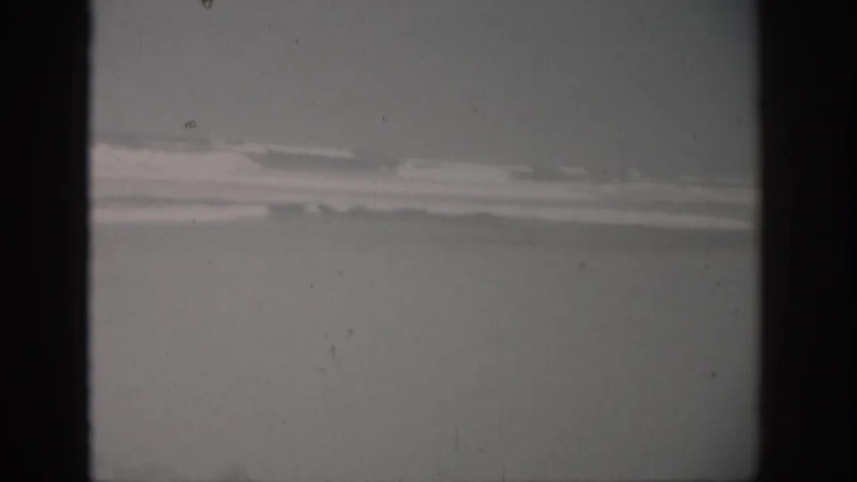 1959 Florida 8mm frame showing rough ocean water and a low, cloudy horizon with visible film grain and dust.