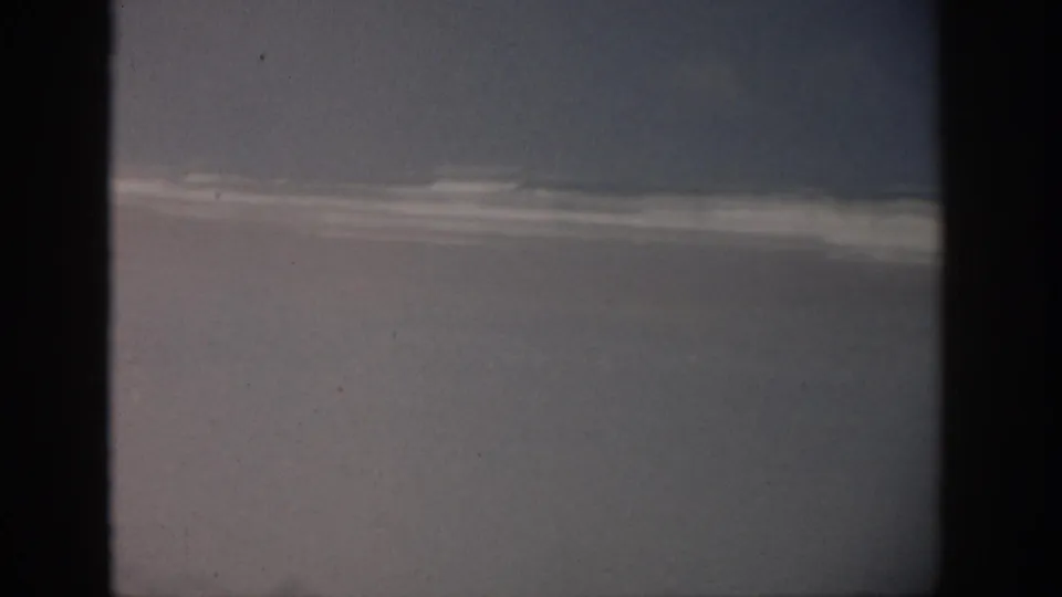 A dim 1959 Florida 8mm frame shows a mostly obscured tank or water surface before the dolphin action becomes visible.