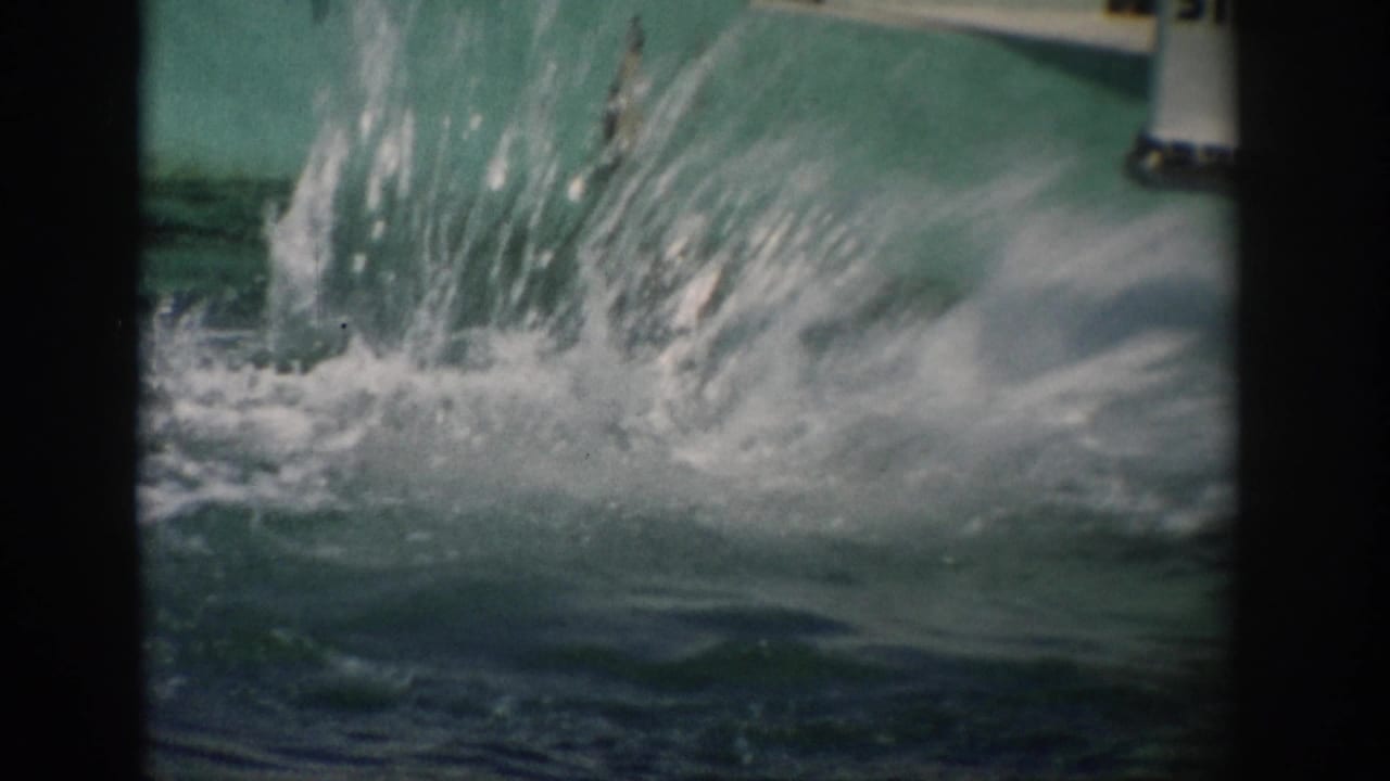 Large splash erupts in turquoise tank water near the frame edge.