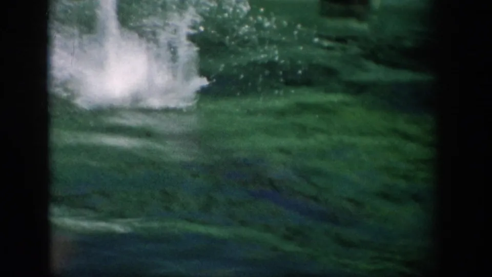 1959 Florida 8mm frame with a large splash in green pool water during the dolphin performance.