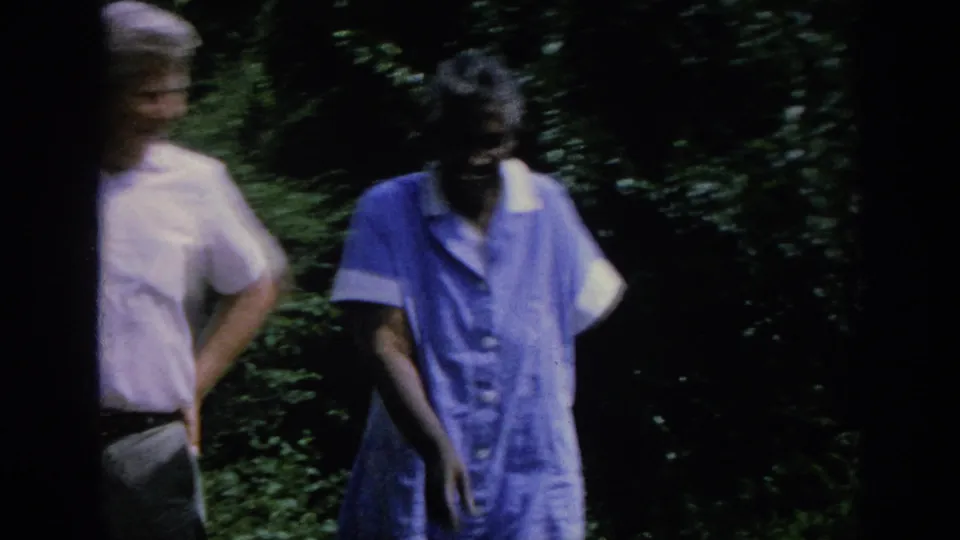 The man and elderly woman move along a leafy outdoor path in the 1962 Blainsport home-movie frame.