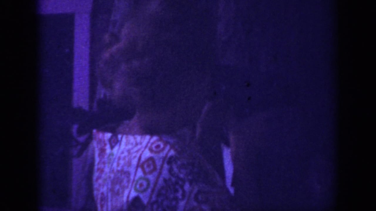 In the 1962 Blainsport footage, the woman turns beside a dark interior frame while grain and purple color shift obscure detail.