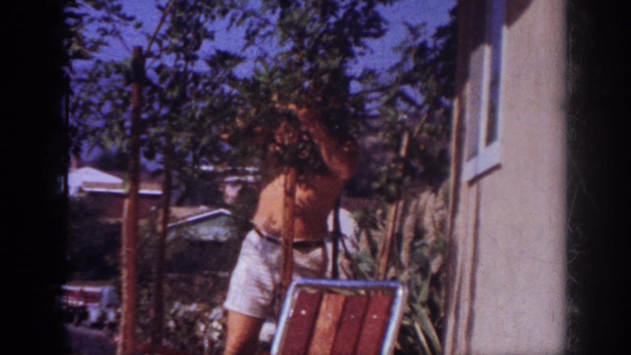 In 1962 Blainsport, Pennsylvania footage, a shirtless man in white shorts stands among potted saplings near a light-colored house wall.