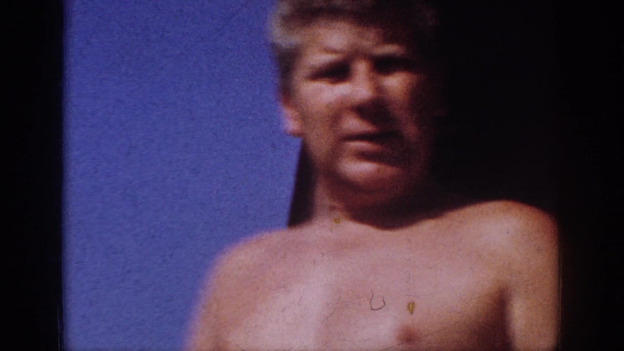 Shirtless adult man in a 1962 Blainsport home-movie frame, softly focused against blue sky with dark film edges.
