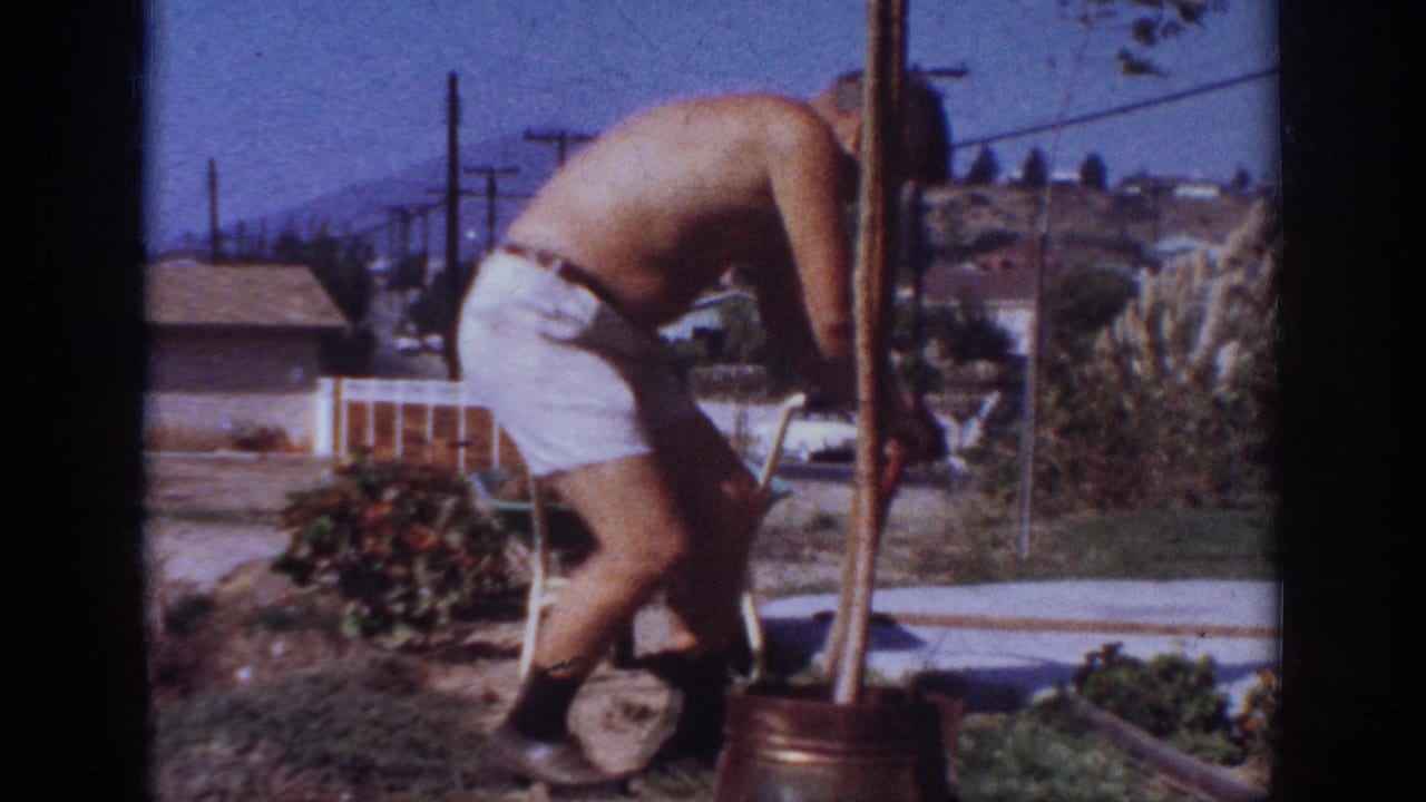 In supplied 1962 Blainsport home-movie footage, a shirtless man bends over a backyard planting area near a shovel, pot, and distant houses.