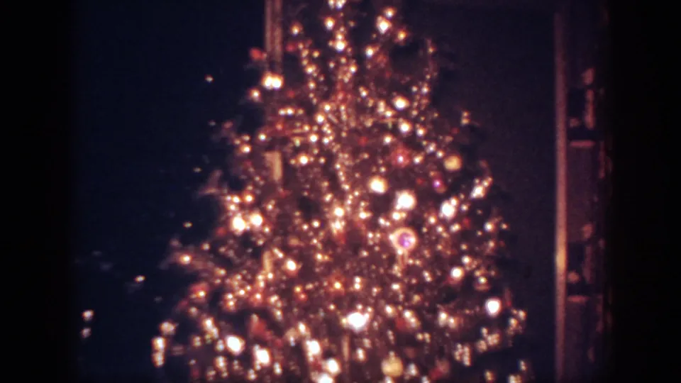 Final 1962 home-movie frame of the glowing decorated tree, with ornaments, lights, and dark interior edges visible.