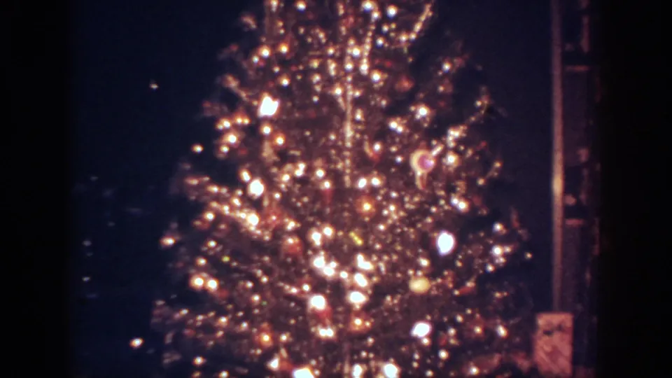 1962 Blainsport frame showing the lower portion of the illuminated Christmas tree and dense decorations.